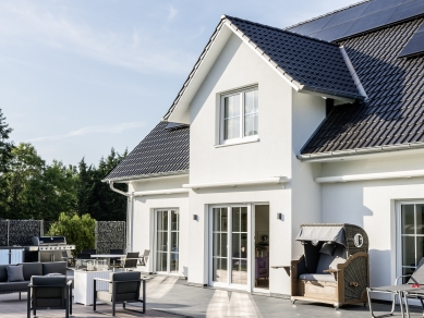 Ein weißes Haus, vom Garten ausgesehen, hat Photovoltaikanlagen installiert.