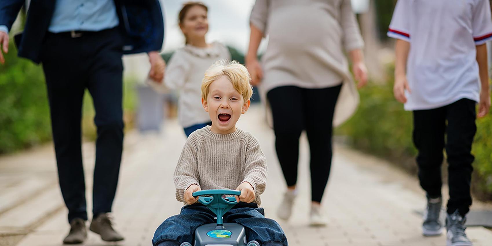 Familie steht in der Einfahrt vor Ihrem Carport und winkt in die Kamera. 