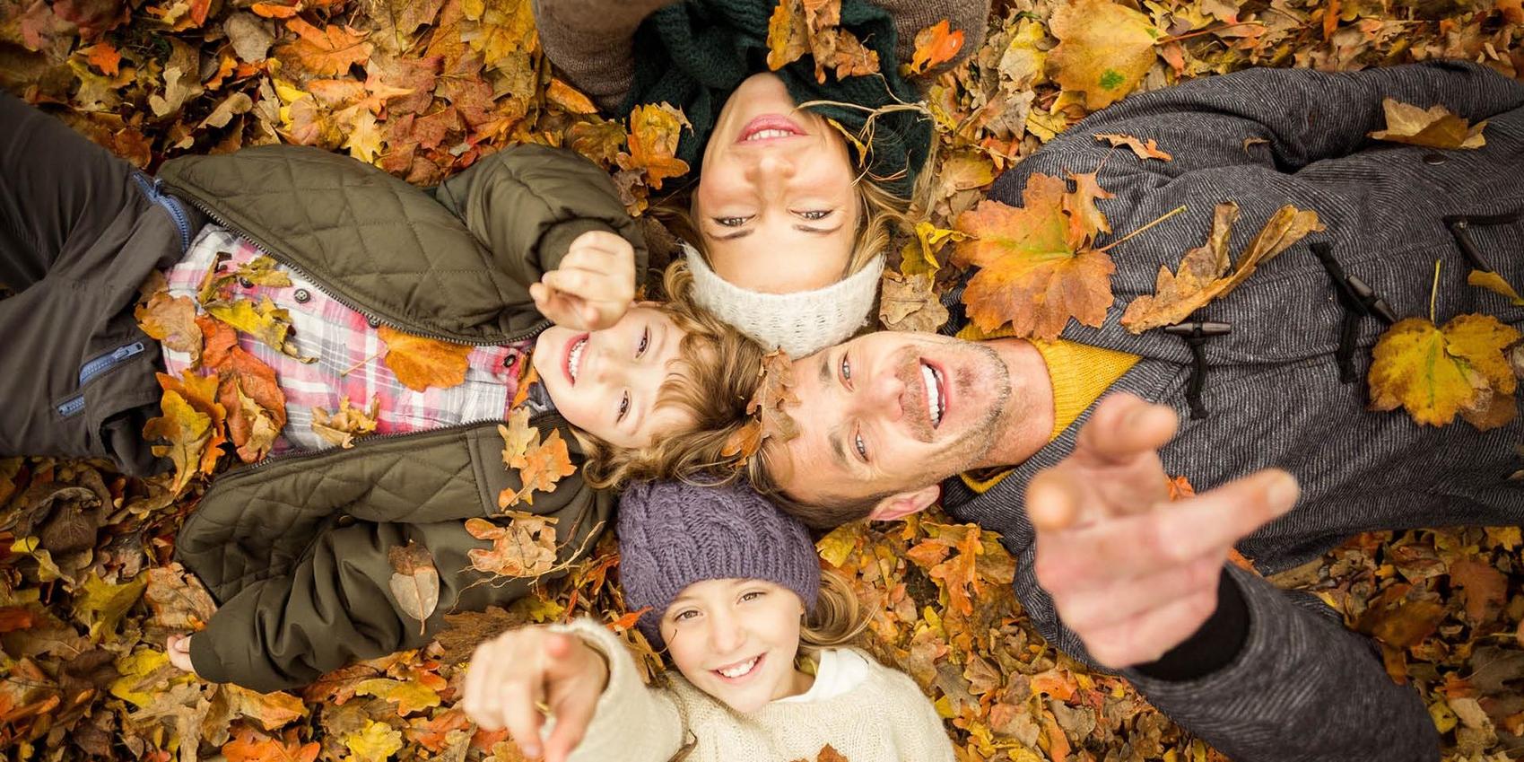 Glückliche Familie liegt im Laub