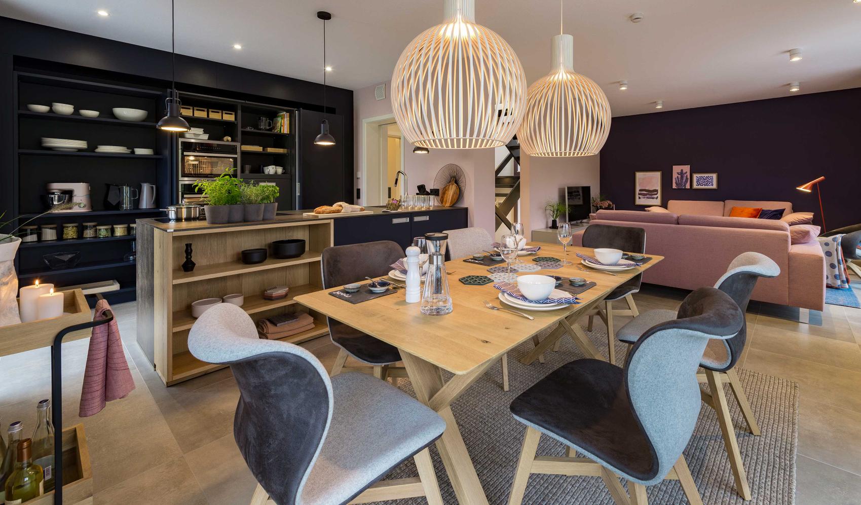 Blick in ein modernes Esszimmer mit Holztisch und offener Küche