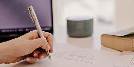 Hand mit einem Stift vor einem Bildschirm