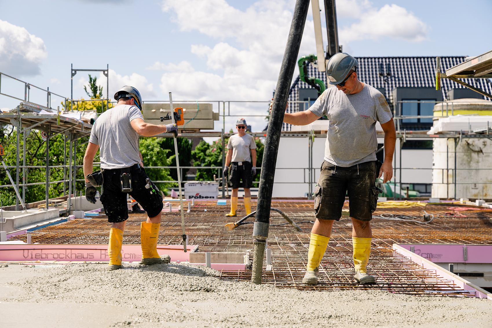 Fertig gedämmte Bodenplatte wird final von Betonarbeitern gegossen