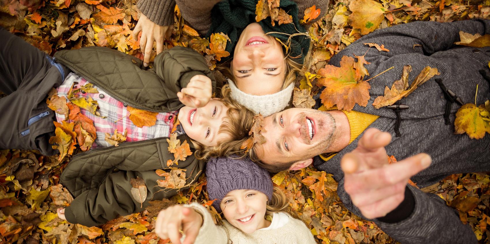 Glückliche Familie liegt im Laub