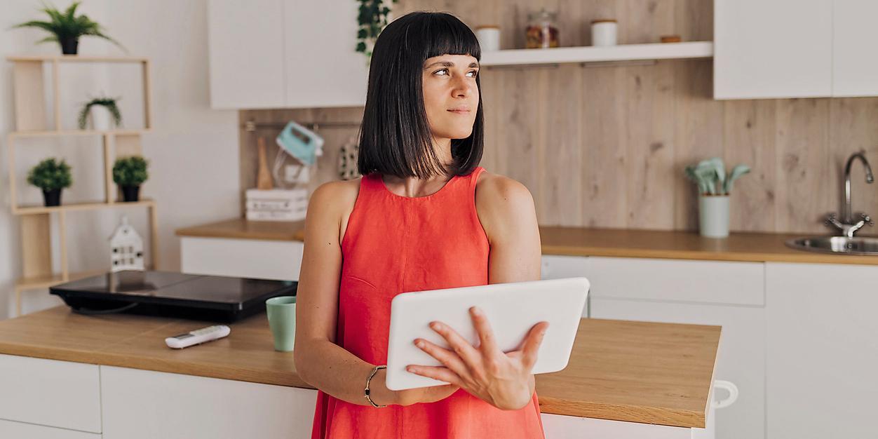 Eine Frau mit einem Laptop in der Hand überlegt