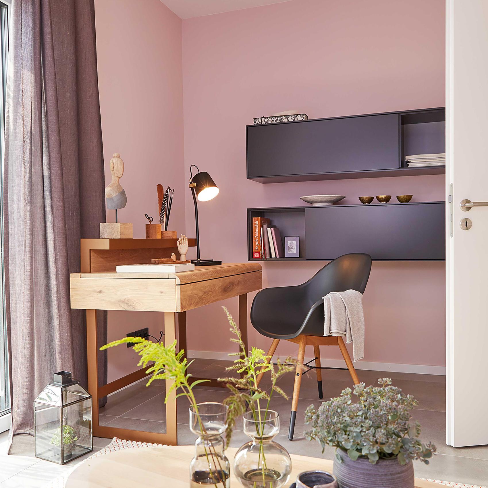 Blick auf einen Homeoffice-Bereich mit rosa Wänden und schwarzen Regalen