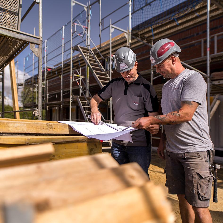 Bauarbeiter besprechen die Hausdämmung vor Ort auf der Baustelle
