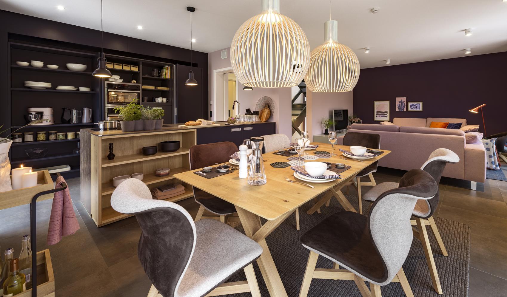 Blick in ein modernes Esszimmer mit Holztisch und offener Küche