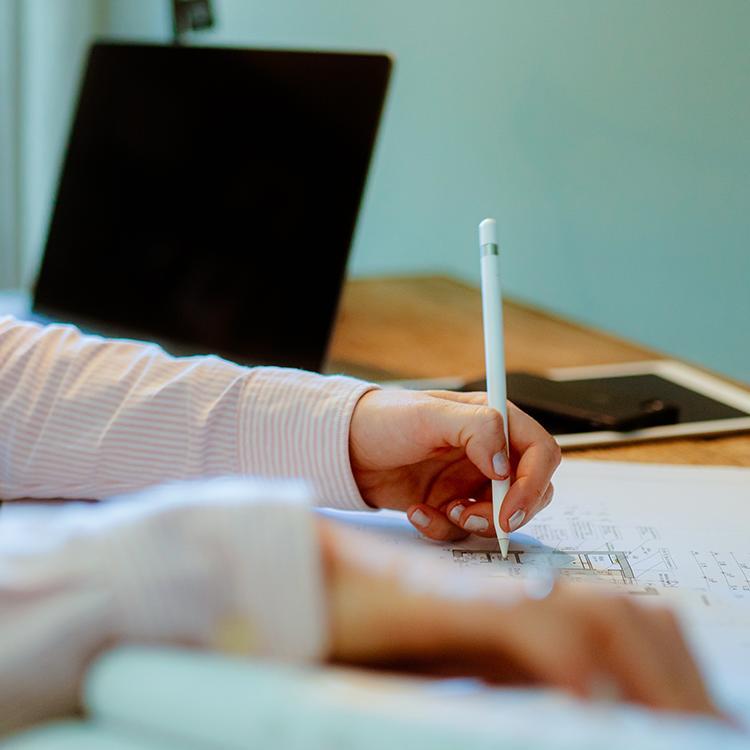 Eine Frau sitzt am Schreibtisch mit einem Stift in der Hand