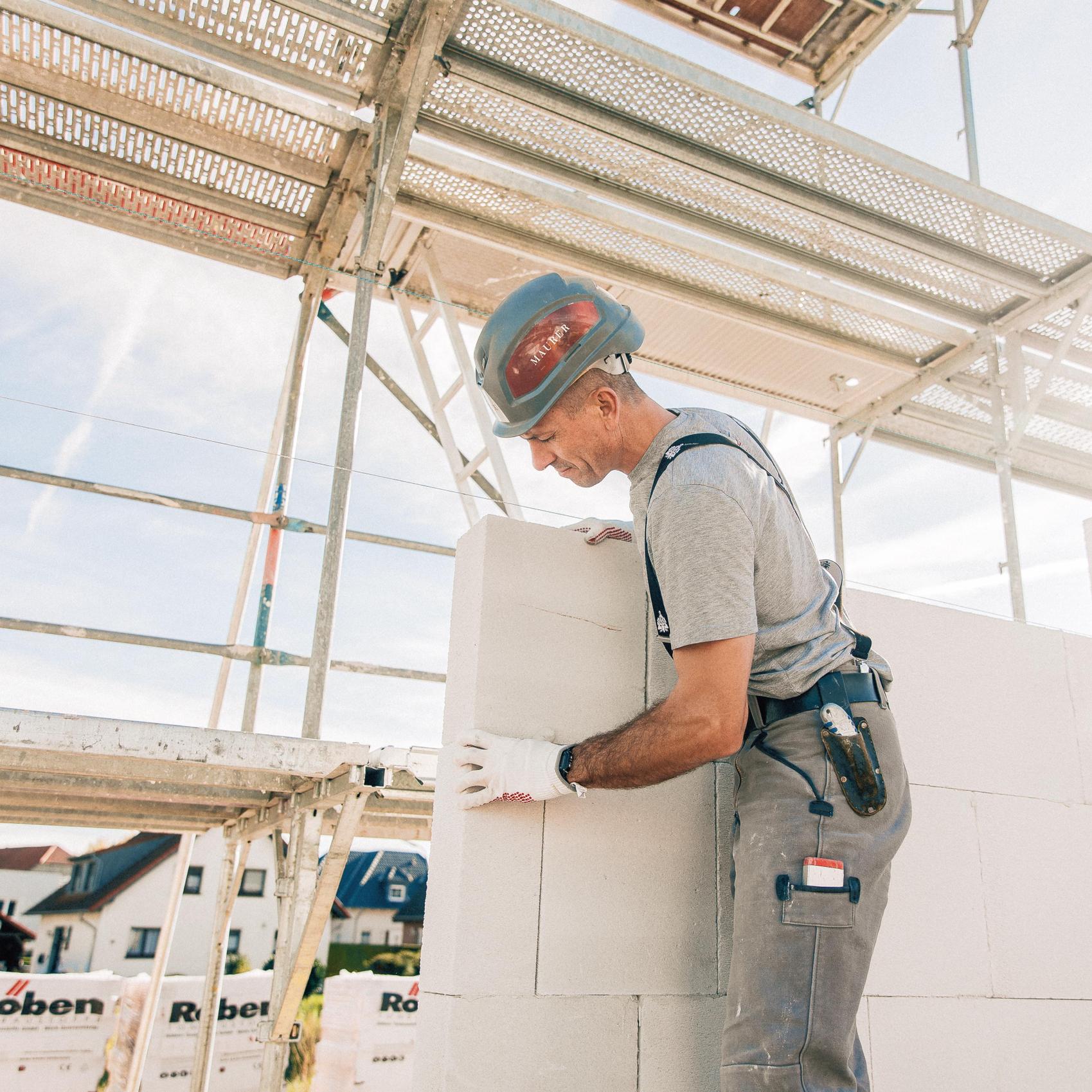 Ein Handwerker setzt Steine auf einer Baustelle von Viebrockhaus