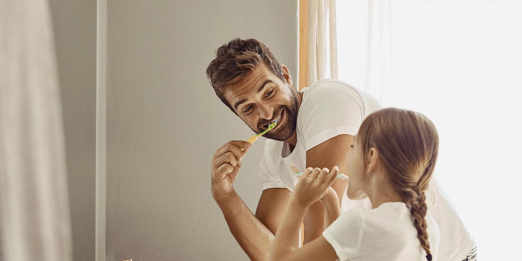 Vater putzt sich gemeinsam mit der Tochter die Zähne